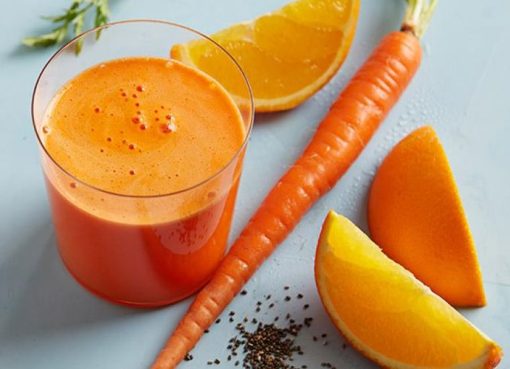 Segelas jus jeruk wortel segar dengan warna oranye cerah, dihiasi potongan jeruk dan wortel di sampingnya, siap untuk dinikmati.